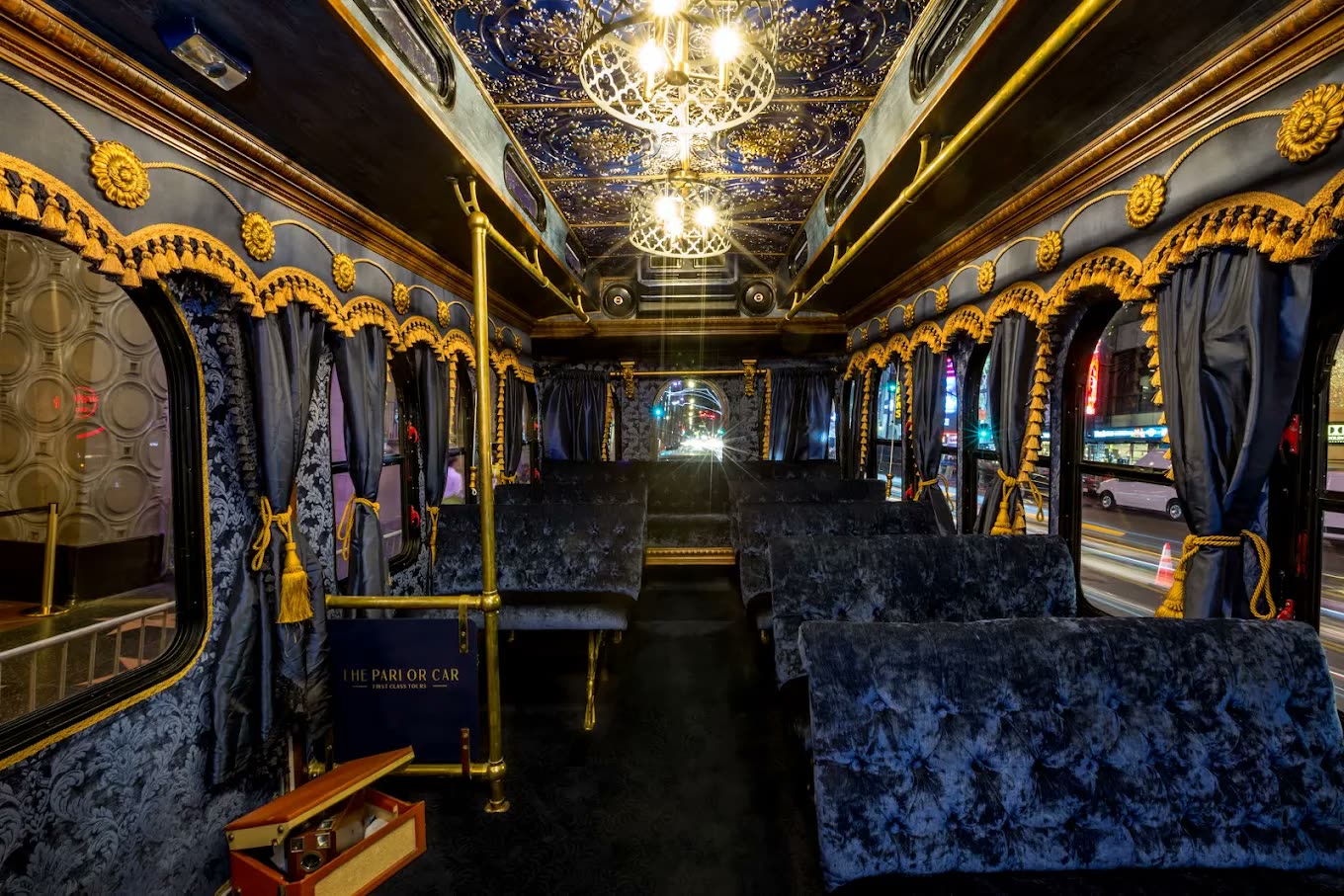 Inside the trolley at night — chandeliers, gold trim and navy velvet seating